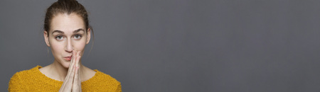 glowing happiness concept - daydreaming 20s girl thinking with hand gesture for reflection and serenity,studio shot on long gray copy space panoramaの写真素材