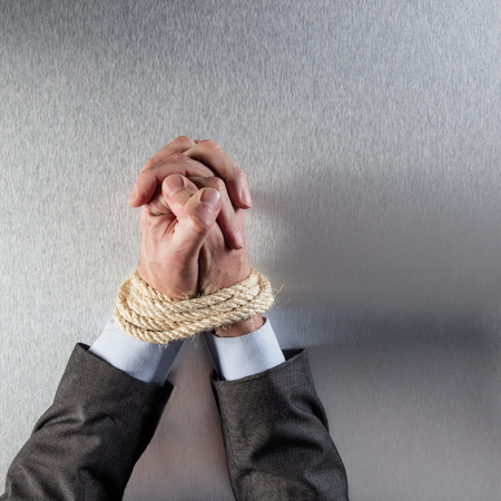 businessman hands tied with a rope praying for concept of employee peace or modern corporate...