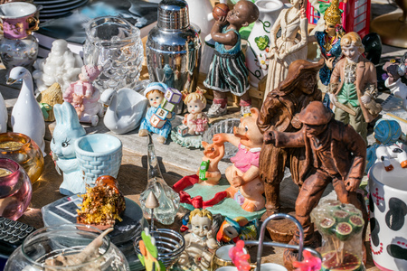 mix of household things and various decoration objects and toys at flea market for second hand, collection or over-consumption at outdoor thrift storeの写真素材