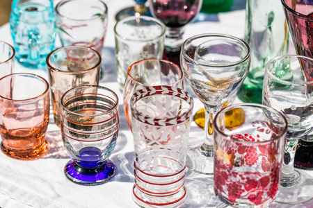 display of retro 50s beautiful glasses in different colors and shapes at garage sale for collection or reusing dishesの写真素材