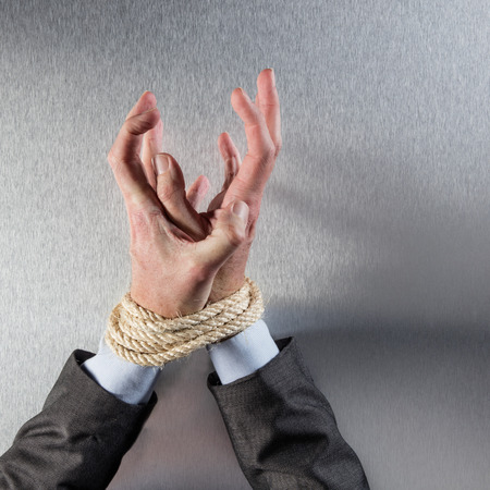 stressed out businessman hands tied with a rope grabbing or seeking for management help for concept of employee despair or modern corporate slavery, top viewの写真素材