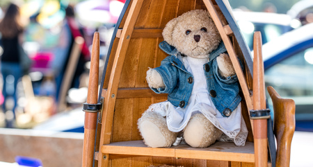 beautiful dressed up teddy bear displayed in wooden library in boat shape for nostalgia second hand use at charity or boot sale outdoorsの写真素材