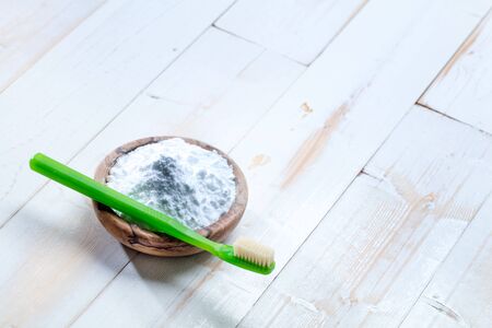 Cleaning and brightening teeth with cheap, natural non-toxic baking soda salt in wooden cup for toothbrush and green dental care on wooden background, copy space, top view still lifeの写真素材