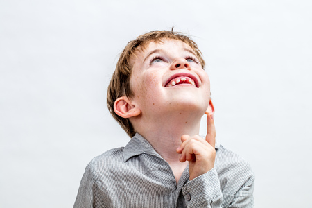 happy imaginative little boy looking away, pointing his finger up for concept of adorable kid...