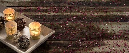 winter still-life with glowing candlelights and wicker balls for rustic decoration on tray over...