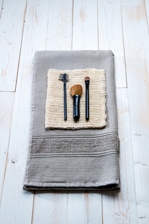 Pure design setup of body care and beauty accessories for eco-friendly make up brushes and exfoliation towels over natural white wooden background, top viewの写真素材