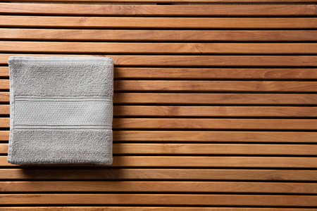 Concept for freshness, hygiene, shower, bath, Turkish bath, spa or body care concept with soft grey cotton towel over beautiful wooden board, beauty spa copy space wallpaper, top viewの写真素材