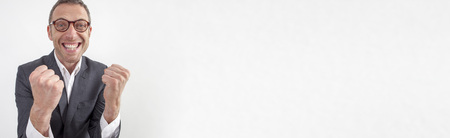 Expressive corporate man concept - Energetic middle age businessman expressing energy and success with hand gesture and toothy smile,wide angle on white long bannerの写真素材