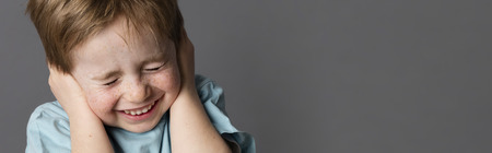 fragile little child closing his ears and eyes against domestic violence or education, having problems with his parents, grey panoramaの写真素材