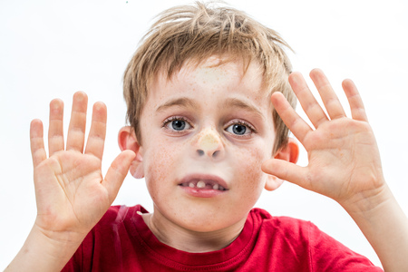 scared little 7-year old child acting for the concept of hostage, violence and sadness, crushing his stuck face and goofy nose to a window with his hands, white backgroundの写真素材
