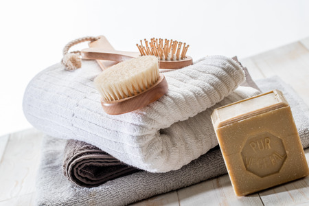 body brush, hairbrush, big solid pure vegetal soap and pile of cotton towels for green friendly shower or traditional bath concept over white wood background, design still life in studioの写真素材