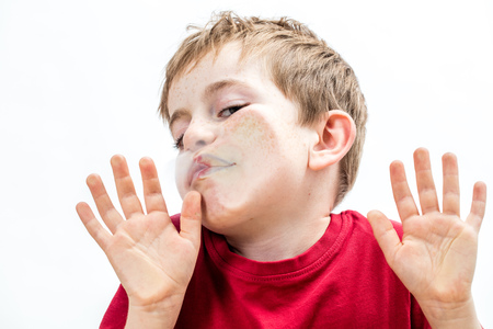 crushed young boy touching his goofy face and cheek to a window with his hands for concept of fear with humor, white backgroundの写真素材