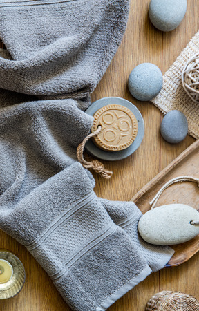 fresh shower and healthy bath concept with grey towel, ethnic solid soap, footcare object and zen stones over wooden background, top viewの写真素材