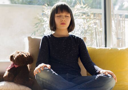 child yoga at home - kid breathing for sunny mindfulness while calm isolation or lockdown from virus pandemic. Girl and boy relaxing with energy - low angle viewの写真素材