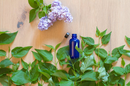 fragranced garden lilac flowers concentrated or captured in glass bottle laid flat in green foliage landscape for natural organic essential oils, beauty or aromatherapy over wooden backgroundの写真素材