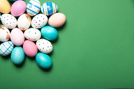 A lot of easter eggs on a green background, place for text, top view,