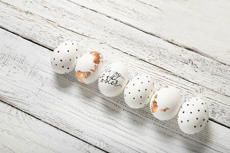 Easter eggs on a white wooden background, place for text, top view