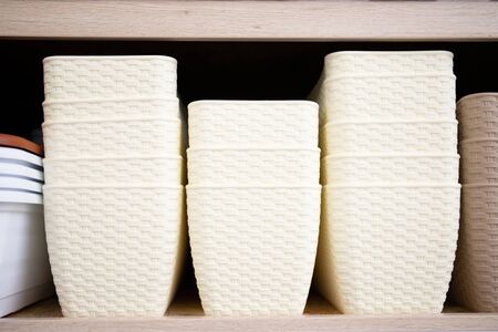 Beige plastic flower pots on a shelf.
