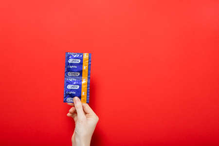 Girl holds condoms Contex. Red background place for text. Kiev, Ukraineのeditorial素材