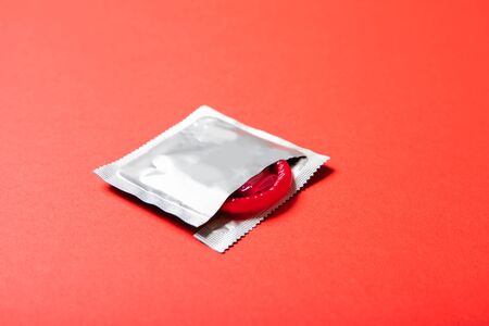 Colored condom on a red background. Medicine and healthcareの写真素材