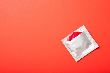 Colored condom on a red background. Place for text, top view. Medicine and healthcareの写真素材