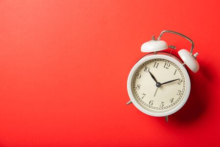 White alarm clock on a red background. Place for text, top view.
