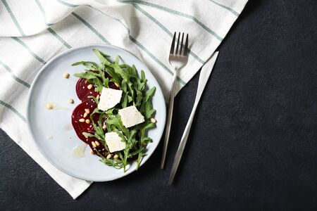 Plate with arugula, beet and feta salad. Sprinkled with pine nuts and honey