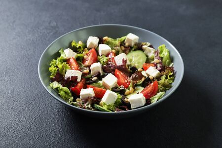 Plate with fresh vegetables salad on a black background. Vegetarian foodの写真素材