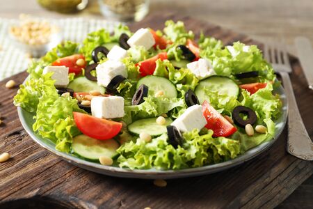 Plate with tasty greek salad of fresh vegetables on wooden backgroundの写真素材