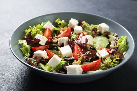 Plate with fresh vegetables salad on a black background. Vegetarian foodの写真素材