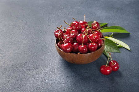 Plate with fresh cherries with green leaves. Black background. Place for textの写真素材