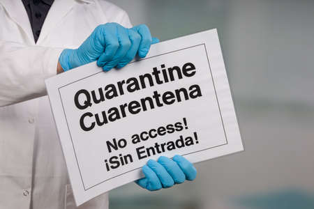 Doctor's hand in medical gloves showing quarantine sign in front of a restricted area