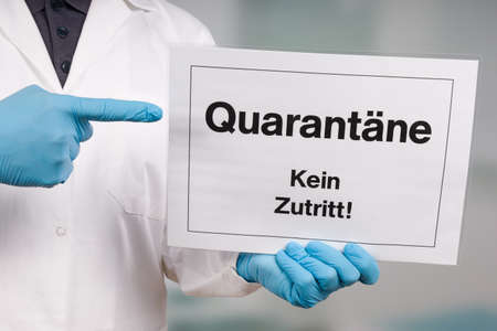 Doctor's hand in medical gloves showing quarantine sign in front of a restricted area