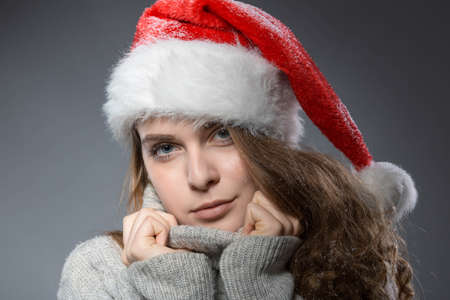 a young and pretty christmas girl with santa claus hat wearing a gray turtleneckの写真素材