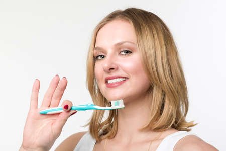 Young blonde woman shows her tooth brush and is smilingの写真素材