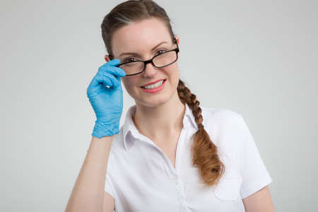 female doctor or nurse in white medical shirt puts on her glassesの写真素材