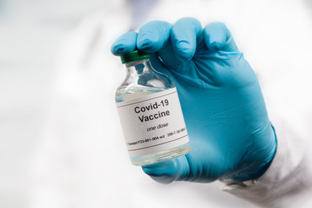 Close up of doctor's hand in medical gloves with a Covid-19 vaccine bottleの写真素材