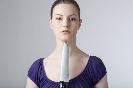 A young woman with a sharp kitchen knifeの写真素材