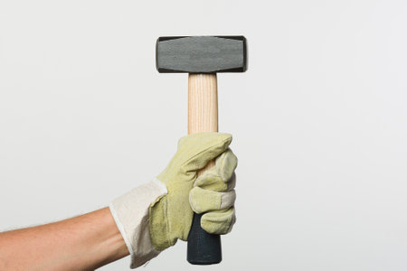 Hand in protective glove holding a hammerの写真素材