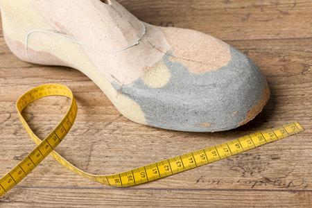 close up of a custom made wooden last with a measuring tape on a wooden workbench