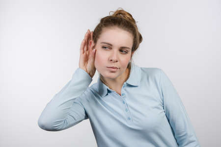 Young woman with hand at her ear tries to listen better