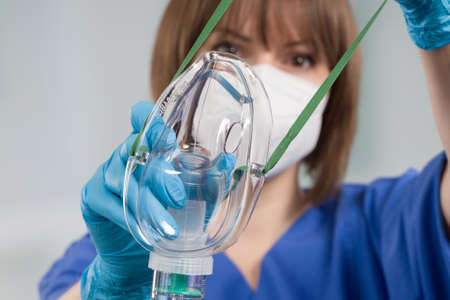 Nurse is applying disposable oxygen mask for breathing support from patient view