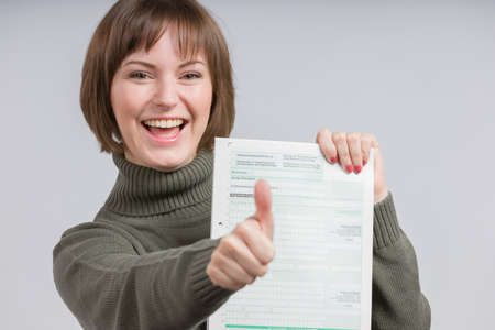 woman holding a tax form smiles happily