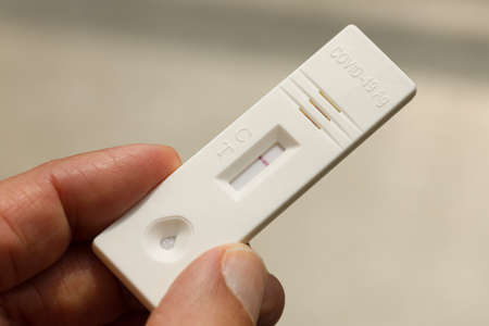 Close up of a hand holding rapid -19 test with a negative result. Express self-test testing at home.