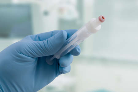 Close up of doctor's hand in medical gloves with an empty syringe ready for taking bloodの写真素材