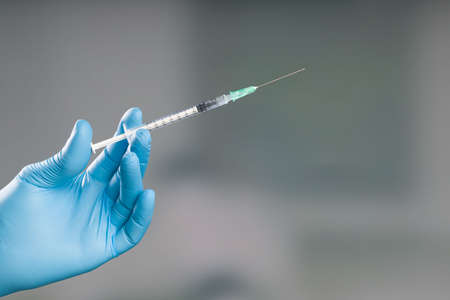 Close-up of doctor's hand in medical gloves with a syringe pulled up with coronavirus or flu vaccine