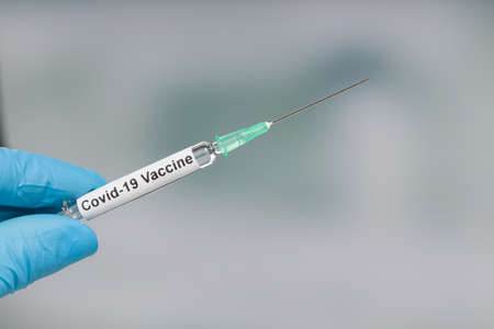 Close up of doctor's hand in medical gloves with a syringe pulled up with Covid-19 vaccine