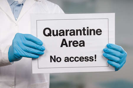 Doctor's hand in medical gloves showing quarantine sign in front of a restricted area
