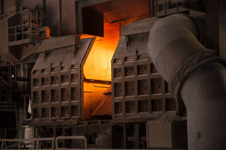 A Bessemer converter in a steel mill with red glowing lightの写真素材