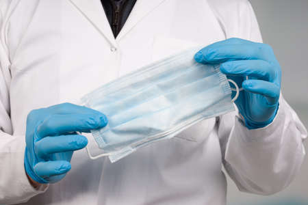 close-up of doctor's hand with a medical face mask for protection against infectionの写真素材